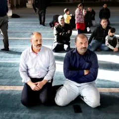 Män sitter på knä i en moské, en del lyssnar uppmärksamt. Kanske diskuterar de en fatwa islam.
