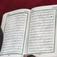 En person läser Koranen, en helig bok inom islam. Texten på sidan kan tolkas som en del av sharia lagar.