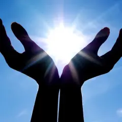 Händer som fångar solljuset, en symbol för hopp och tro inom abrahamitiska religioner.