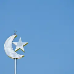 En glänsande halvmåne med en stjärna, en symbol för islam, mot en klarblå himmel.