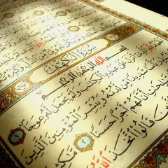 En öppen Koran med texten Surah Al-Kahf. Ljuset faller över sidorna med arabisk skrift.