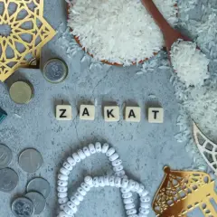 Rismängd, mynt och en bok bredvid bokstäverna som bildar ordet "Zakat", en viktig del av islamisk välgörenhet.