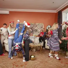En glad familj firar jul i juliga kläder. En kvinna gör en handstående, en annan dansar med en man i en julkostym. En muslimsk jul kan se ut så här, med glädje och gemenskap.