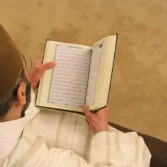 Man i brun hatt läser Koranen. Fajr-bönen består av två rakat.