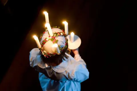 En flicka med ljus i håret, en svensk tradition. Frågan om det är haram att fira jul är komplex och beror på tolkning.