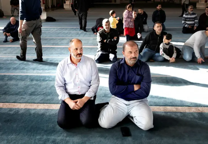 Män sitter på knä i en moské, en del lyssnar uppmärksamt. Kanske diskuterar de en fatwa islam.