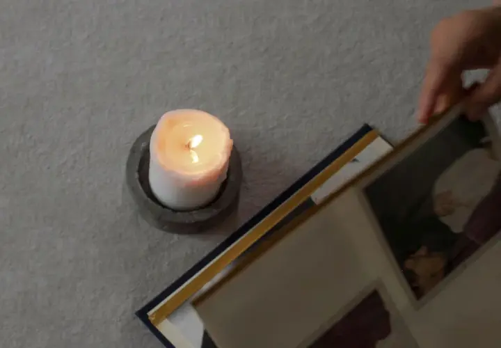 Ett tänt ljus och en fotoalbum. En hand bläddrar i albumet, kanske för att minnas någon. En dua när någon dör.
