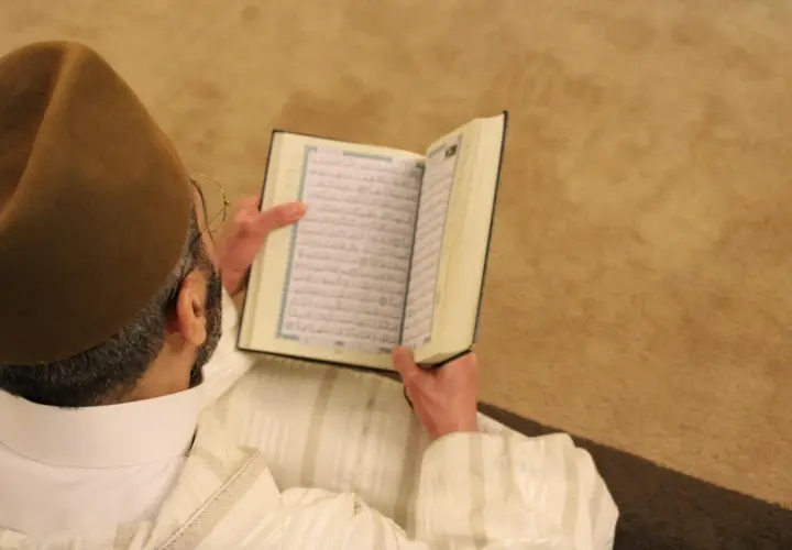 Man i brun hatt läser Koranen. Fajr-bönen består av två rakat.
