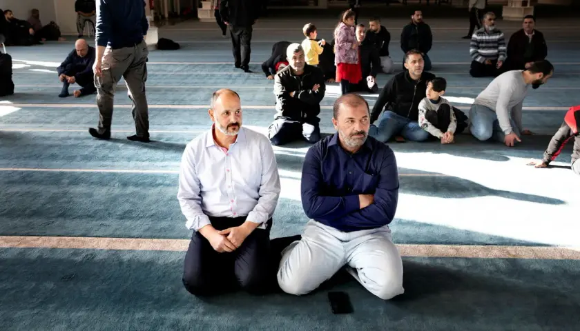 Män sitter på knä i en moské, en del lyssnar uppmärksamt. Kanske diskuterar de en fatwa islam.