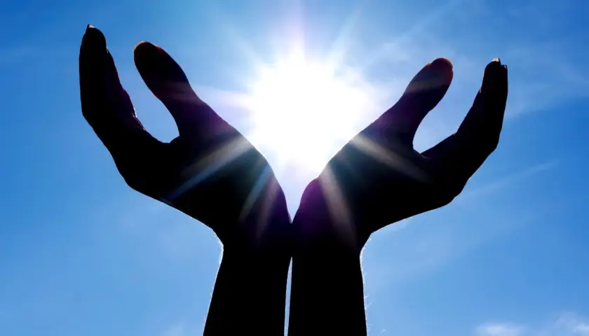 Händer som fångar solljuset, en symbol för hopp och tro inom abrahamitiska religioner.