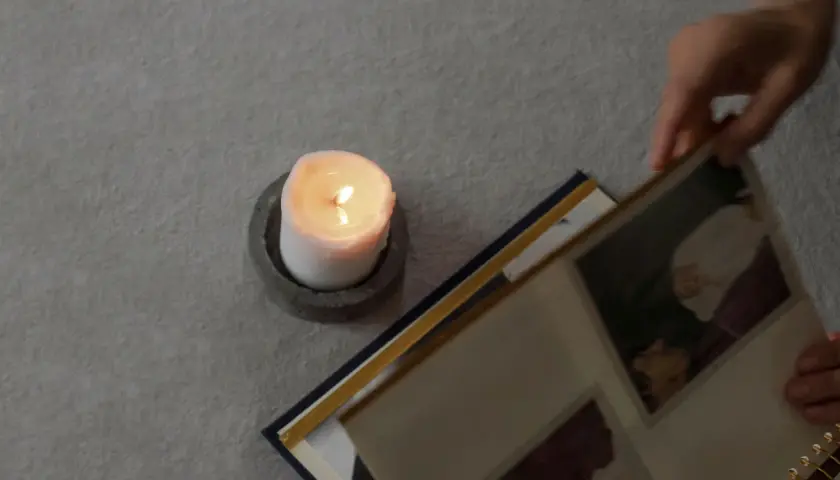 Ett tänt ljus och en fotoalbum. En hand bläddrar i albumet, kanske för att minnas någon. En dua när någon dör.