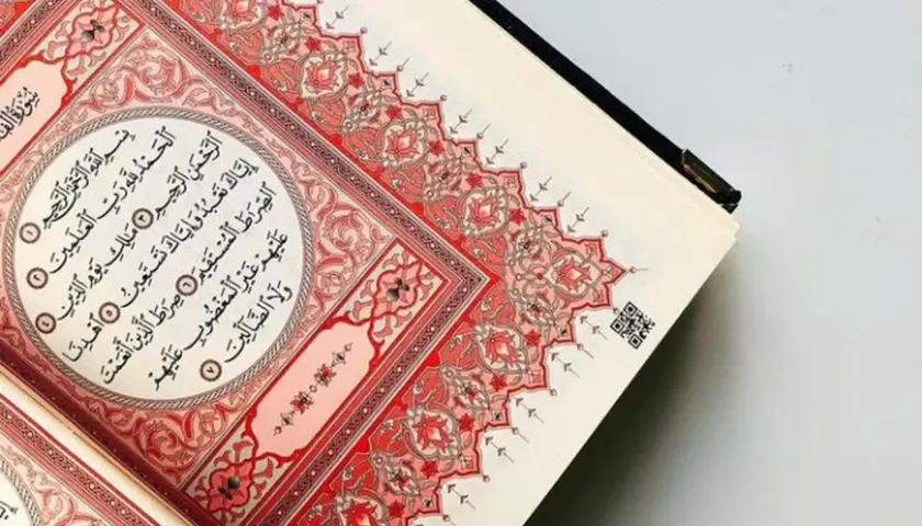 En öppen Koran med vackra röda mönster. Sura Al-Fatiha, den första suran i Koranen, visas.