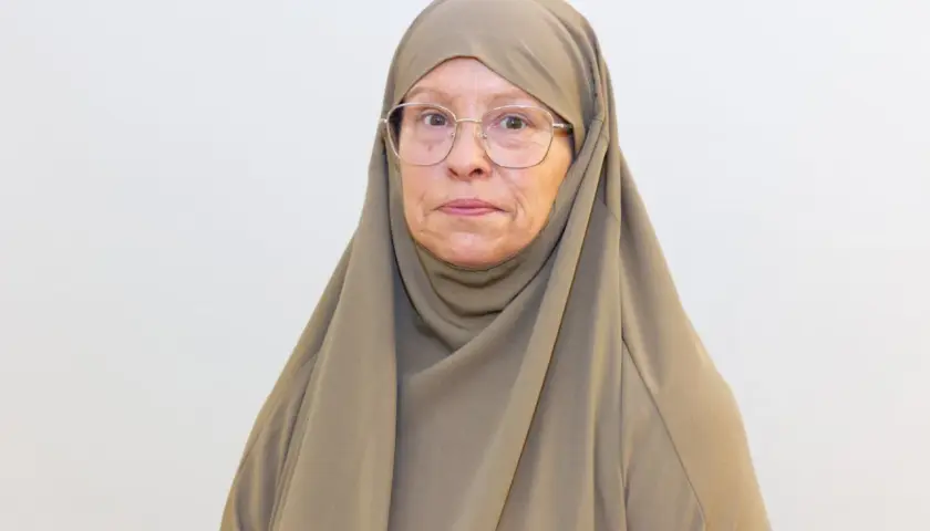 Äldre kvinna med hijab och glasögon, funderar på om det är haram att fira födelsedagar.