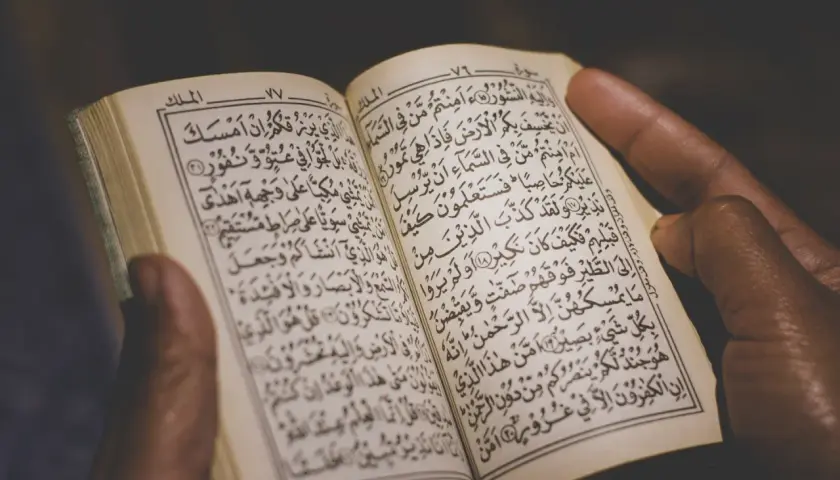 Händer håller en öppen Koran, där kraftfulla Koranverser läses.