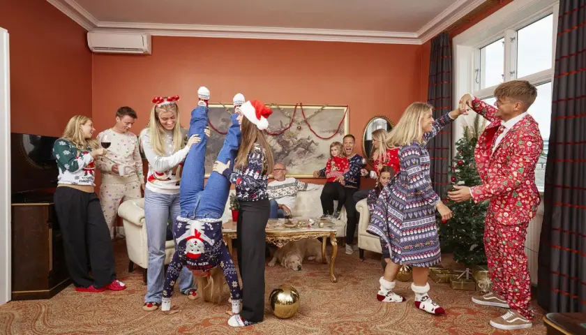 En glad familj firar jul i juliga kläder. En kvinna gör en handstående, en annan dansar med en man i en julkostym. En muslimsk jul kan se ut så här, med glädje och gemenskap.
