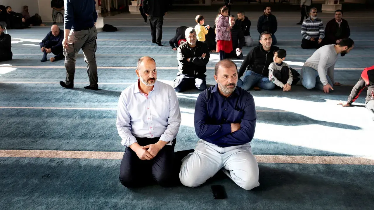 Män sitter på knä i en moské, en del lyssnar uppmärksamt. Kanske diskuterar de en fatwa islam.