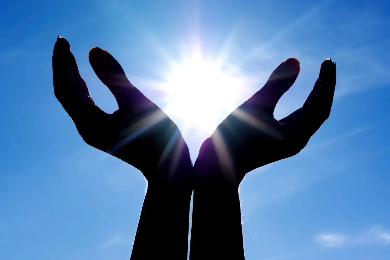 Händer som fångar solljuset, en symbol för hopp och tro inom abrahamitiska religioner.