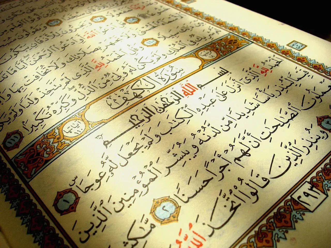 En öppen Koran med texten Surah Al-Kahf. Ljuset faller över sidorna med arabisk skrift.