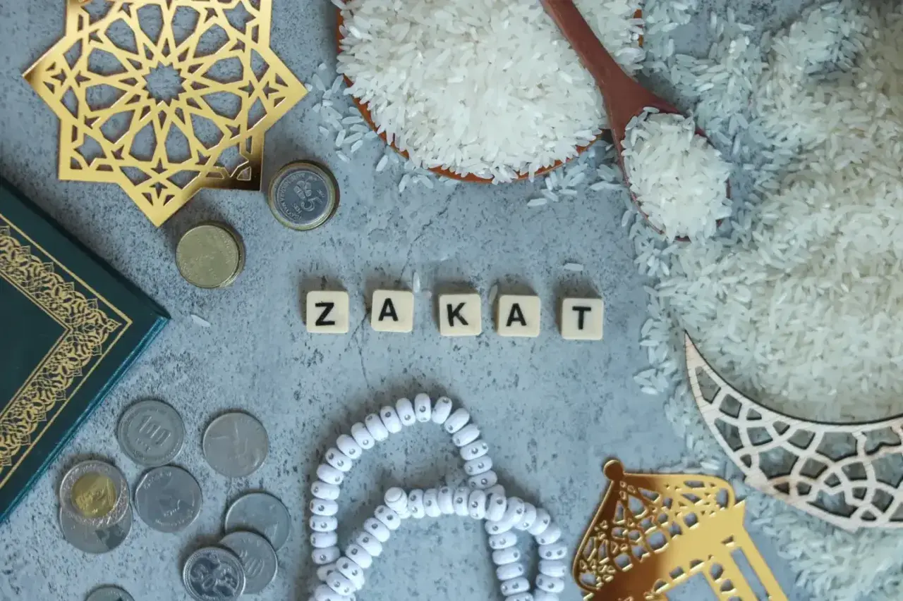 Rismängd, mynt och en bok bredvid bokstäverna som bildar ordet "Zakat", en viktig del av islamisk välgörenhet.