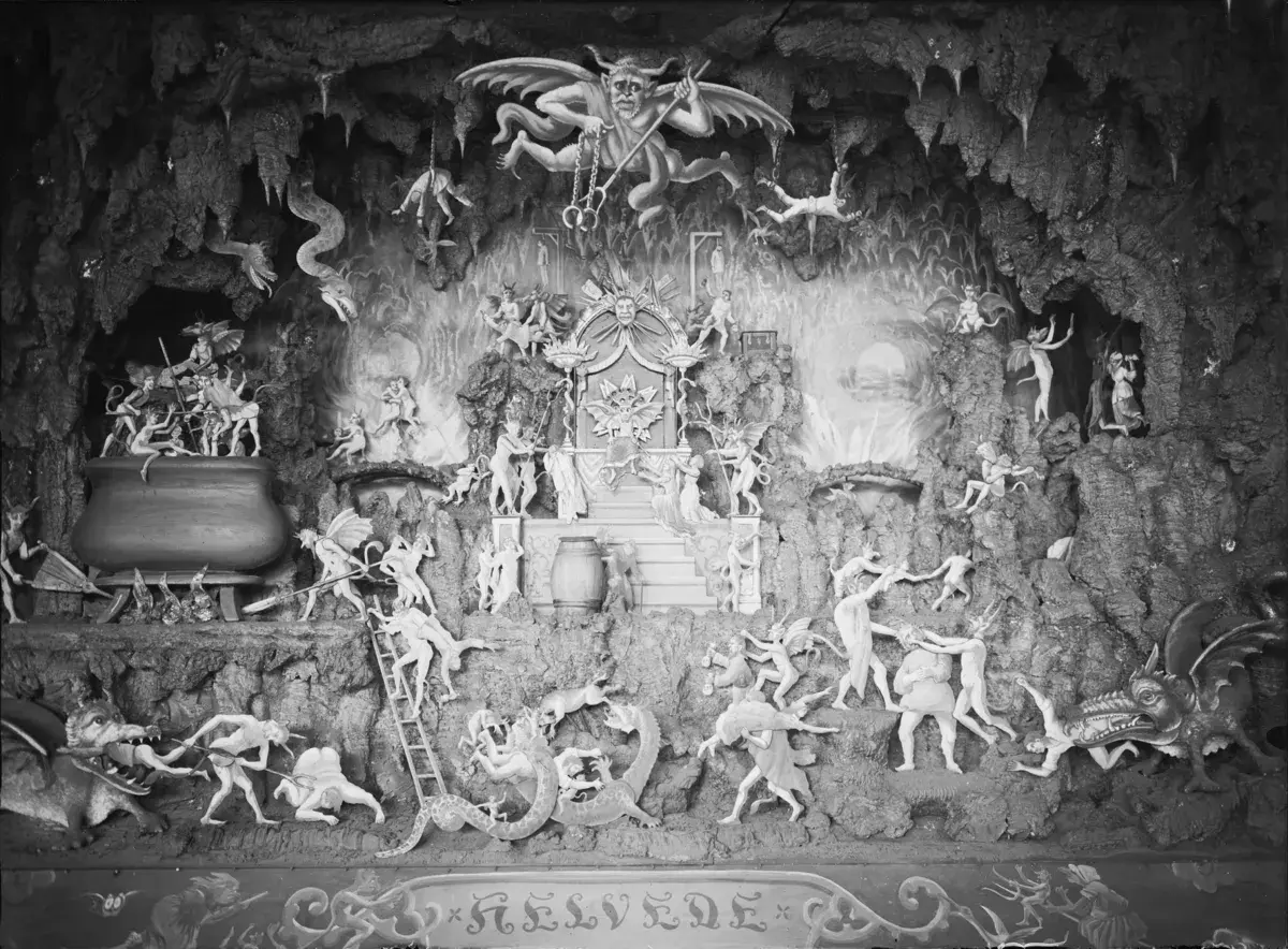 En detaljerad diorama visar scener av helvetet i islam, med demoner som plågar själar i en grottliknande miljö.