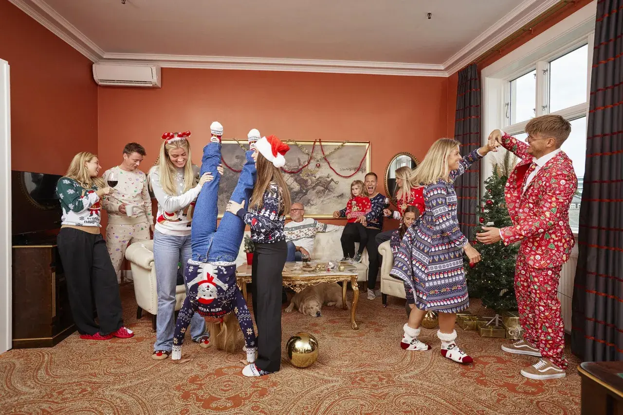 En glad familj firar jul i juliga kläder. En kvinna gör en handstående, en annan dansar med en man i en julkostym. En muslimsk jul kan se ut så här, med glädje och gemenskap.
