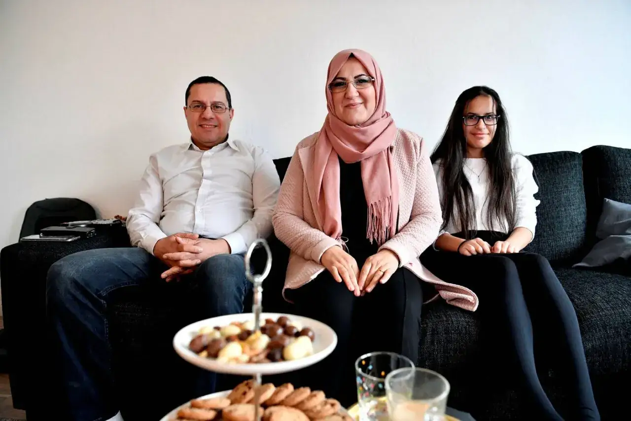 Familj samlad för en mysig muslimsk jul. De sitter på en soffa med en bricka med godsaker framför sig.
