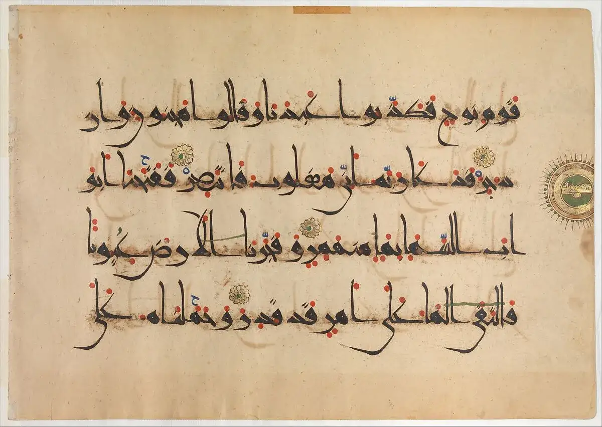 Gammal Koran-text med arabisk kalligrafi. Texten är skriven med svart bläck på pergament, med röda och blå prickar som vokalisering. En cirkulär miniatyr med en grön bakgrund syns till höger.