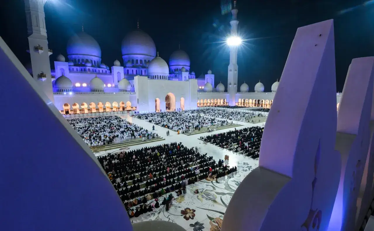 Stor moské upplyst på natten, tusentals människor samlade för bön, en scen som påminner om Surah Al Qadr.