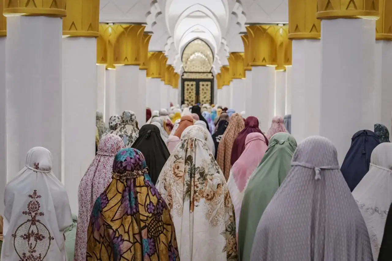 Kvinnor i färggranna sjalar ber tillsammans i en moské, en vacker scen av umma islam.